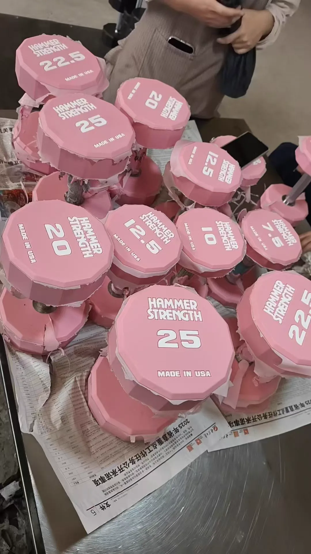Batch of custom pink CPU dumbbells with private label weight markings during production review
