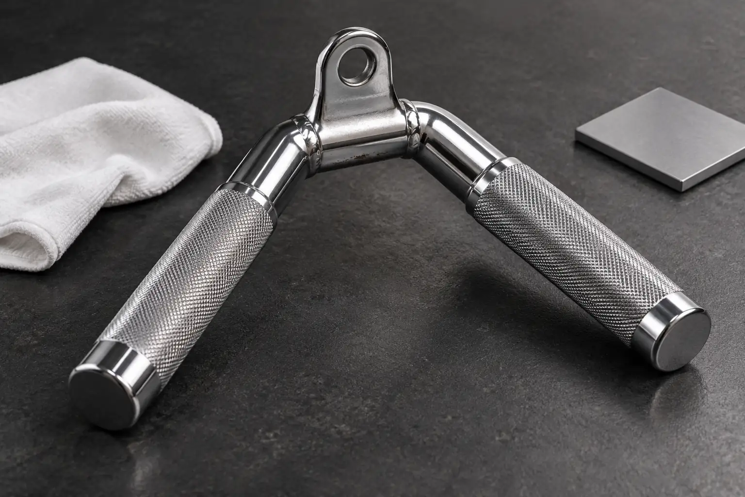 Accessorio cavo cromato a V senza marchio su piano scuro con panno bianco e piccoli punti di corrosione presso la giunzione